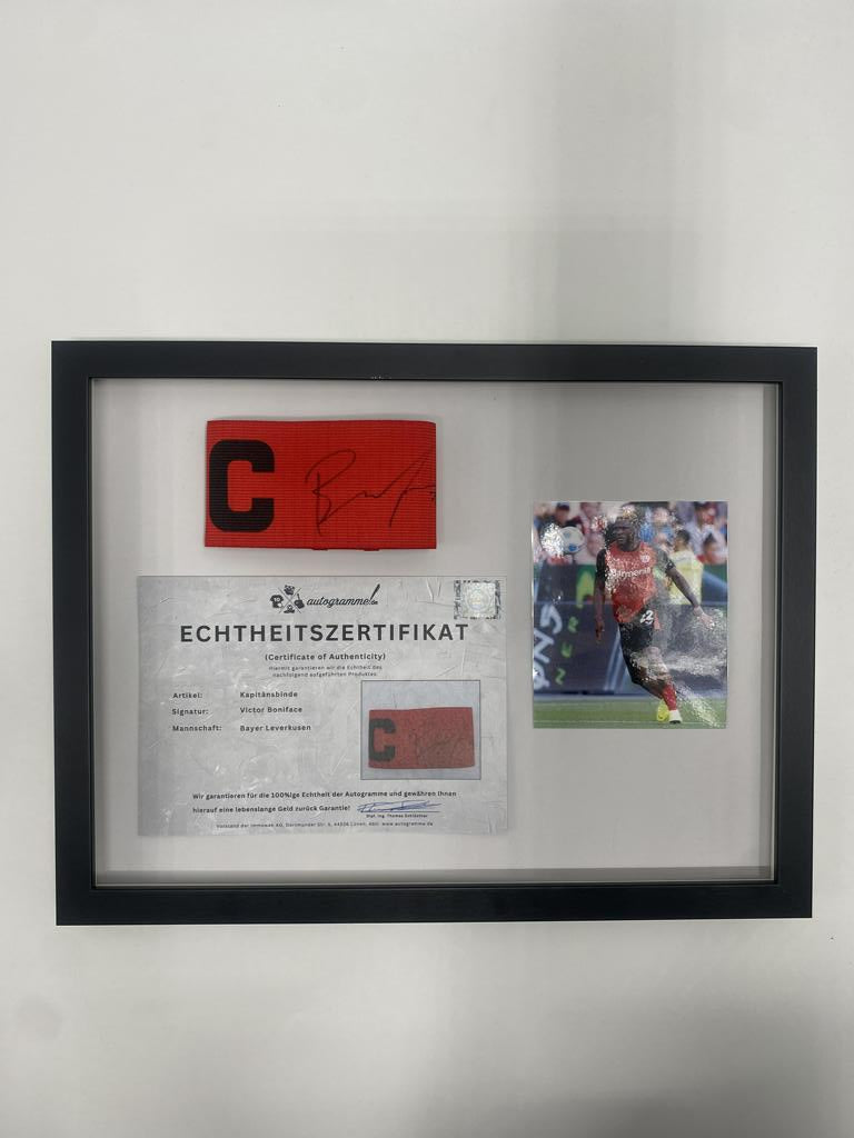 Captain's armband signed by Victor Boniface in a Bayer Leverkusen frame. Autograph