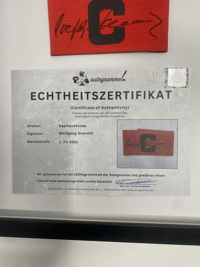 Captain's armband signed by Wolfgang Overath in a framed 1. FC Köln autograph COA