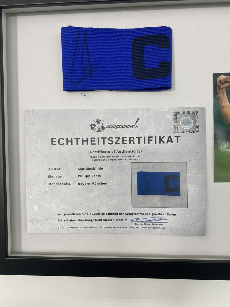 Brazalete de capitán firmado por Philipp Lahm en un marco de autógrafos del Bayern de Múnich.