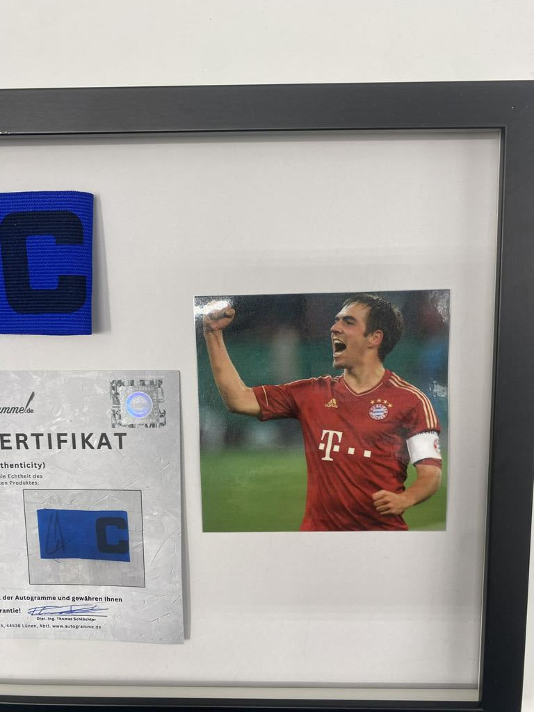 Brazalete de capitán firmado por Philipp Lahm en un marco de autógrafos del Bayern de Múnich.