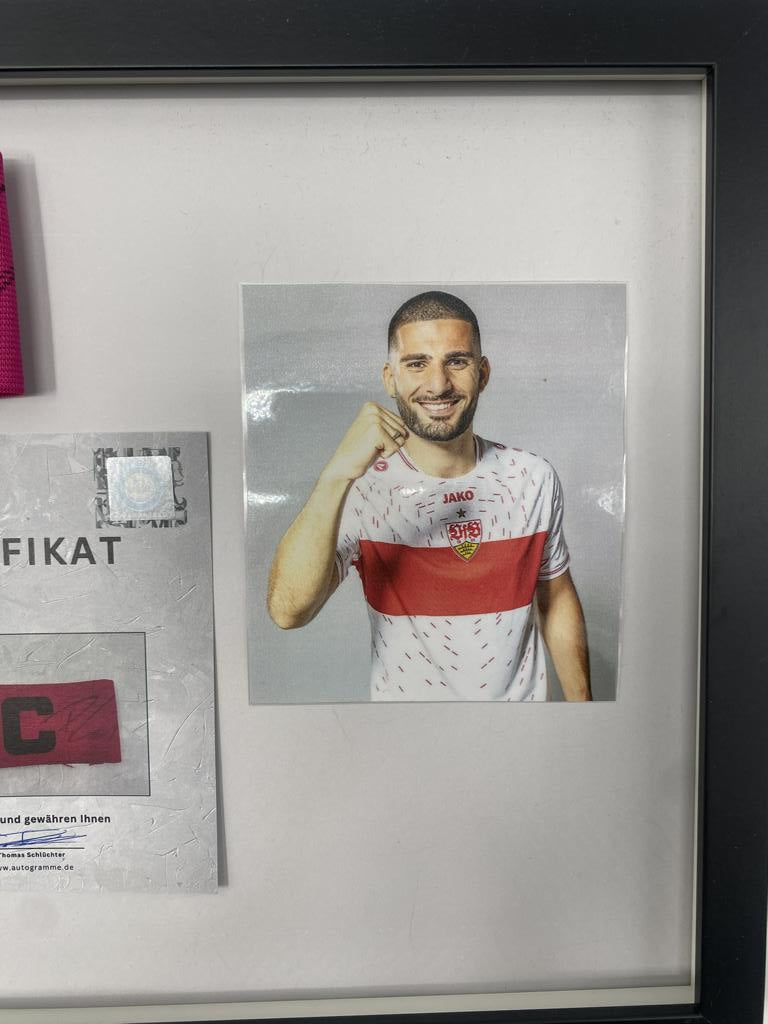 Brazalete de capitán firmado por Deniz Undav en un marco de autógrafos del VfB Stuttgart.
