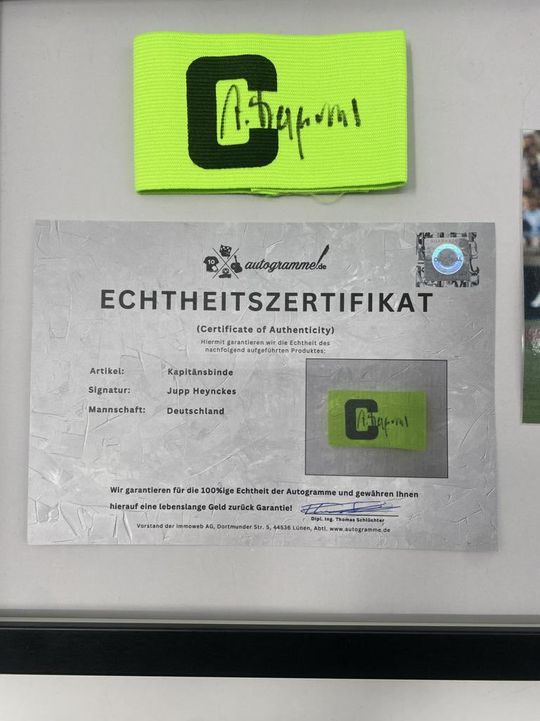 Brazalete de capitán firmado por Jupp Heynckes enmarcado, Alemania. Autógrafo.