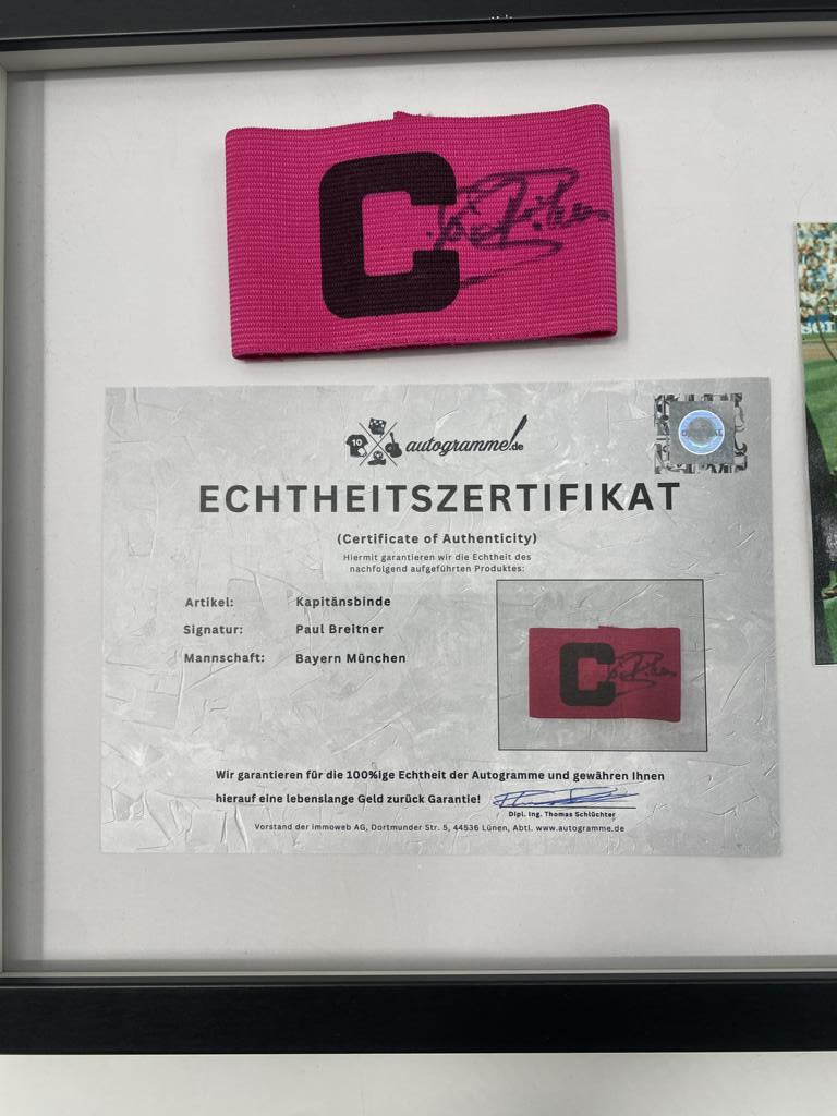 Brazalete de capitán firmado por Paul Breitner en un marco de autógrafos del Bayern de Múnich.