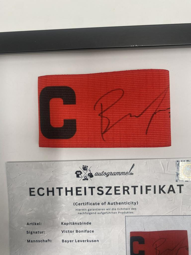 Captain's armband signed by Victor Boniface in a Bayer Leverkusen frame. Autograph