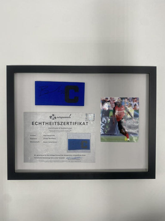 Kapitänsbinde Victor Boniface signiert im Rahmen Bayer Leverkusen Autogramm