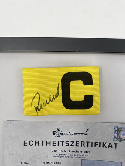 Captain's armband signed by Guido Buchwald in a Germany Football autograph frame