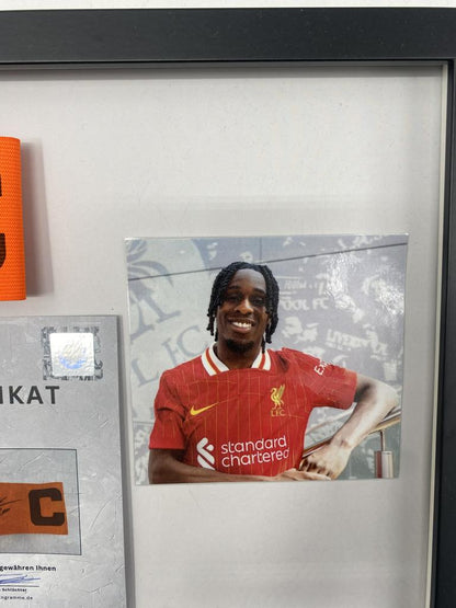 Brazalete de capitán firmado por Jeremie Frimpong en un marco con autógrafo del FC Liverpool