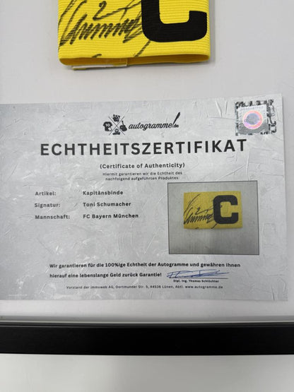 Kapitänsbinde Toni Schumacher signiert im Rahmen FC Bayern München Fußball Autogramm