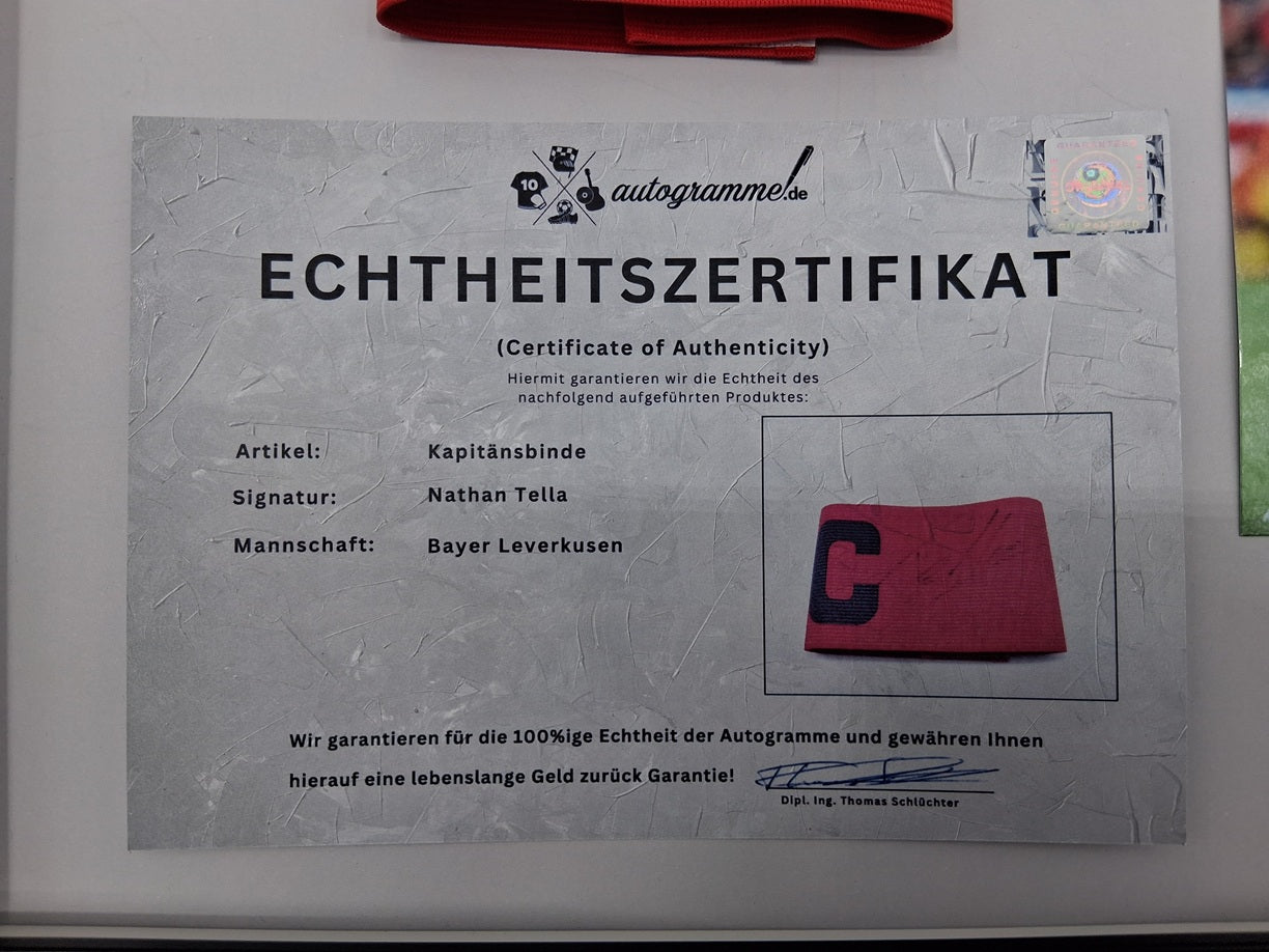 Kapitänsbinde Nathan Tella signiert im Rahmen Bayer Leverkusen Autogramm