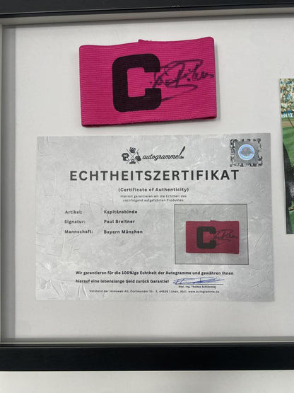Brazalete de capitán firmado por Paul Breitner en un marco de autógrafos del Bayern de Múnich.